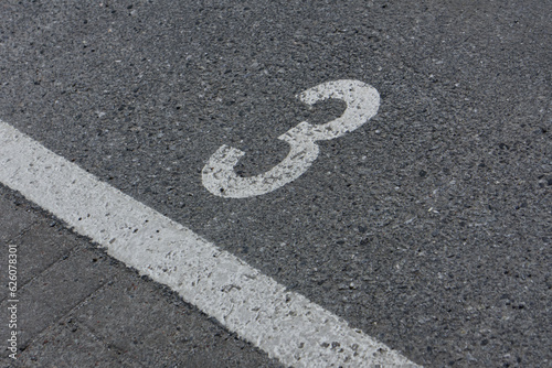 a number 3 painted on asphalt parking spot