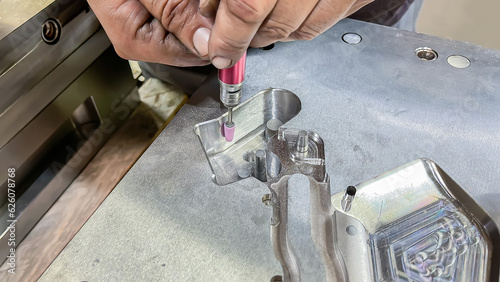 a toolmaker adjusting a plastic injection mold with a grinder, mechanical adjustment of a mold, die setter adjusting hands working