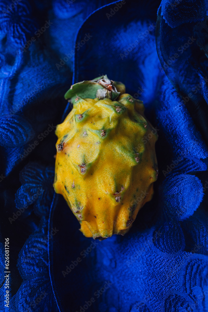 yellow whole dragon fruit, dragonfruit, pitaya on cobalt blue fabric
