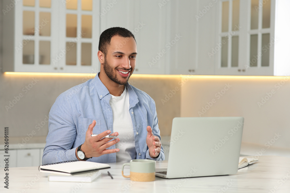 Young man having online video chat at desk in kitchen. Home office Young man having online video chat at desk in kitchen. Home office