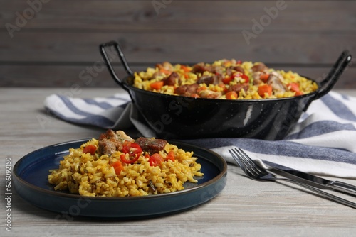 Delicious pilaf with meat, carrot and chili pepper on wooden table