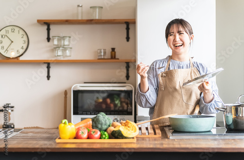 キッチンで料理の味見をするエプロン姿の女性・主婦（カフェ）
 photo