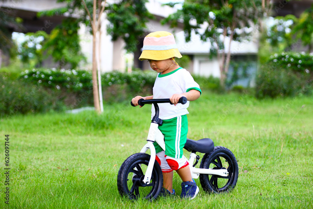 Fototapeta premium Boy riding balance bike on dirt path in the park