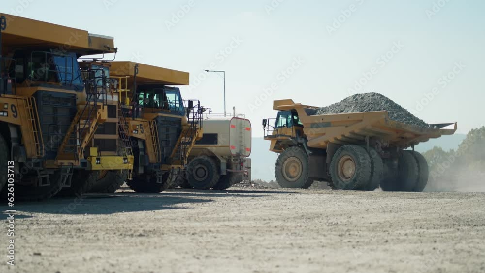 Big dumper trucks on a construction site transporting ore from open mine pit, slow motion Big dumper trucks on a construction site transporting ore from open mine pit, slow motion