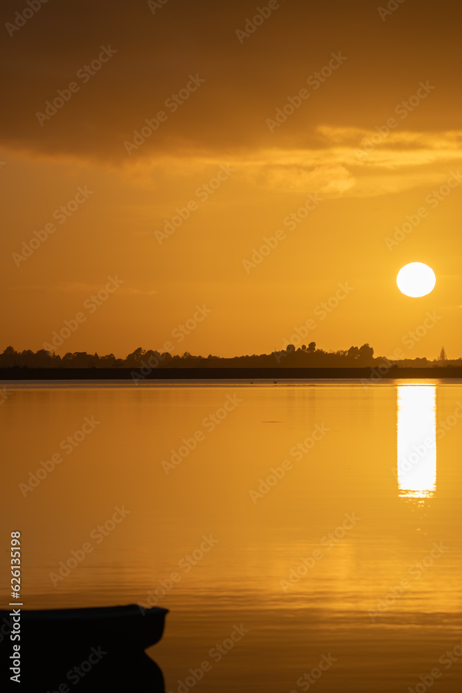 Golden sunrise with glow of round sun rising above horizon