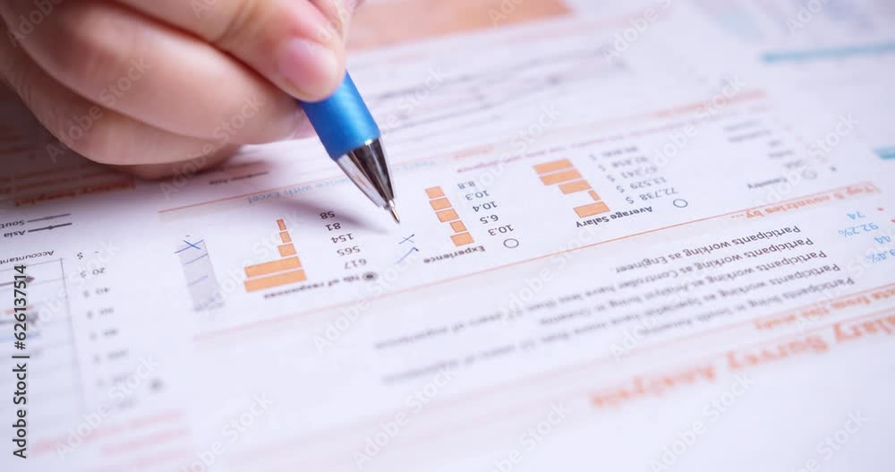 Close-up of businesswoman's hands with pen working at office desk and analyzing graphs and charts, profit report checking. Female hands with pen-filling papers Close-up of businesswoman's hands with pen working at office desk and analyzing graphs and charts, profit report checking. Female hands with pen-filling papers