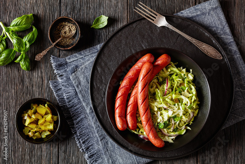 cooked sausages with coleslaw salad in black bowl