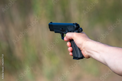 A gun in the hands of a man close-up in nature.
