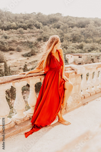 Woman red dress. Summer lifestyle of a happy woman posing near a fence with balusters over the sea.