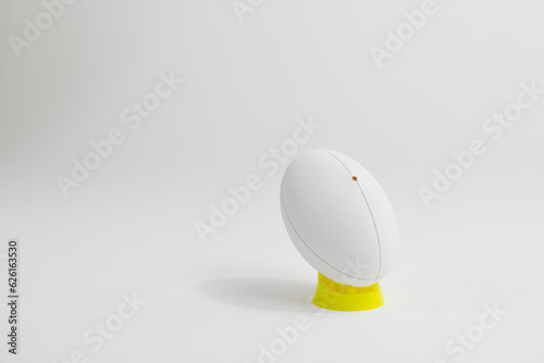 White rugby ball on yellow stand with copy space on white background
