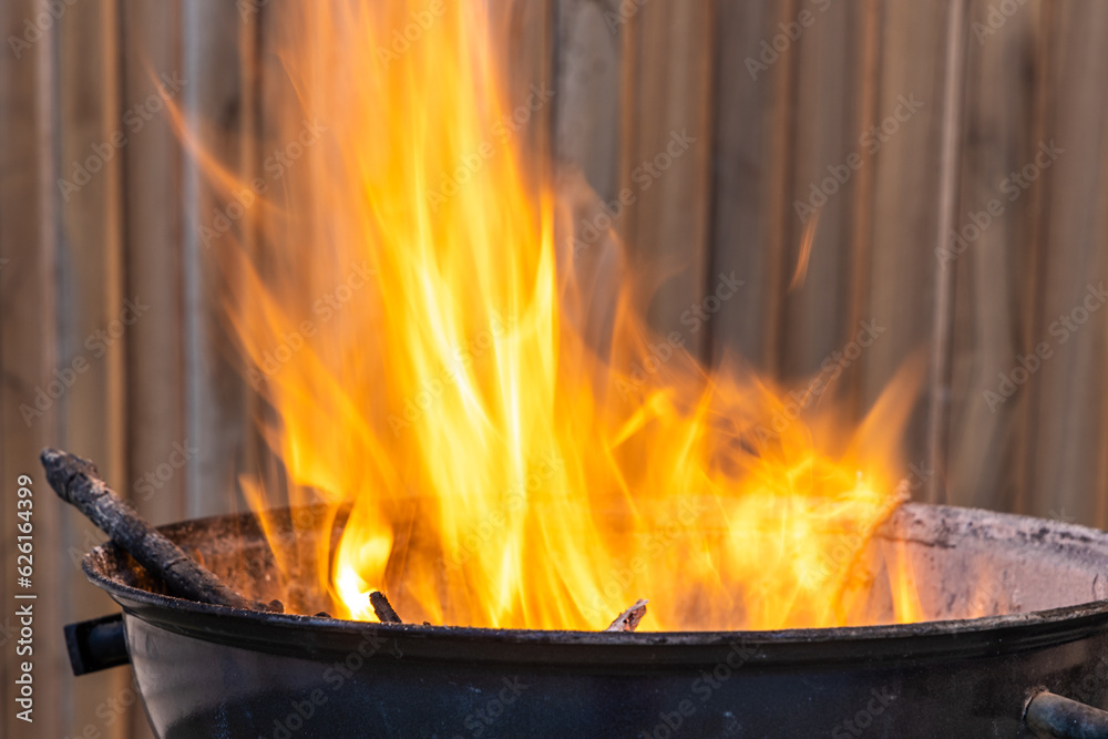 Black metal round barbeque with fire for a picnic is in the terrace Black metal round barbeque with fire for a picnic is in the terrace
