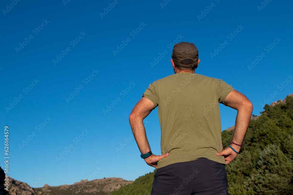 Man dressed in military green t-shirt and cap and sunglasses enjoying a day in the mountains