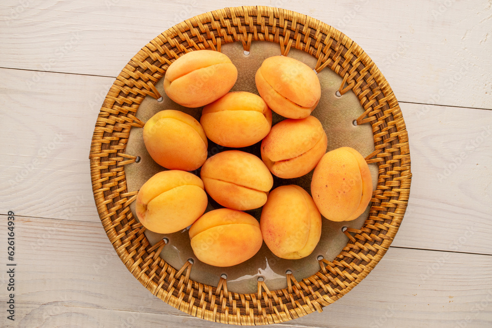 Several ripe juicy apricots in a ceramic plate on a wooden table, macro, top view. Several ripe juicy apricots in a ceramic plate on a wooden table, macro, top view.