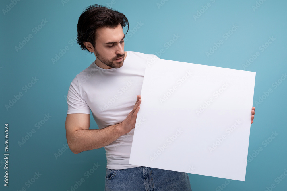 cute brutal brunette guy holding a paper sheet with empty space for information cute brutal brunette guy holding a paper sheet with empty space for information