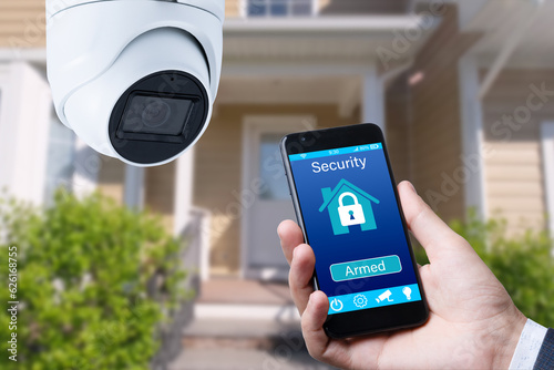 Security camera and smart home app, private house on the background.