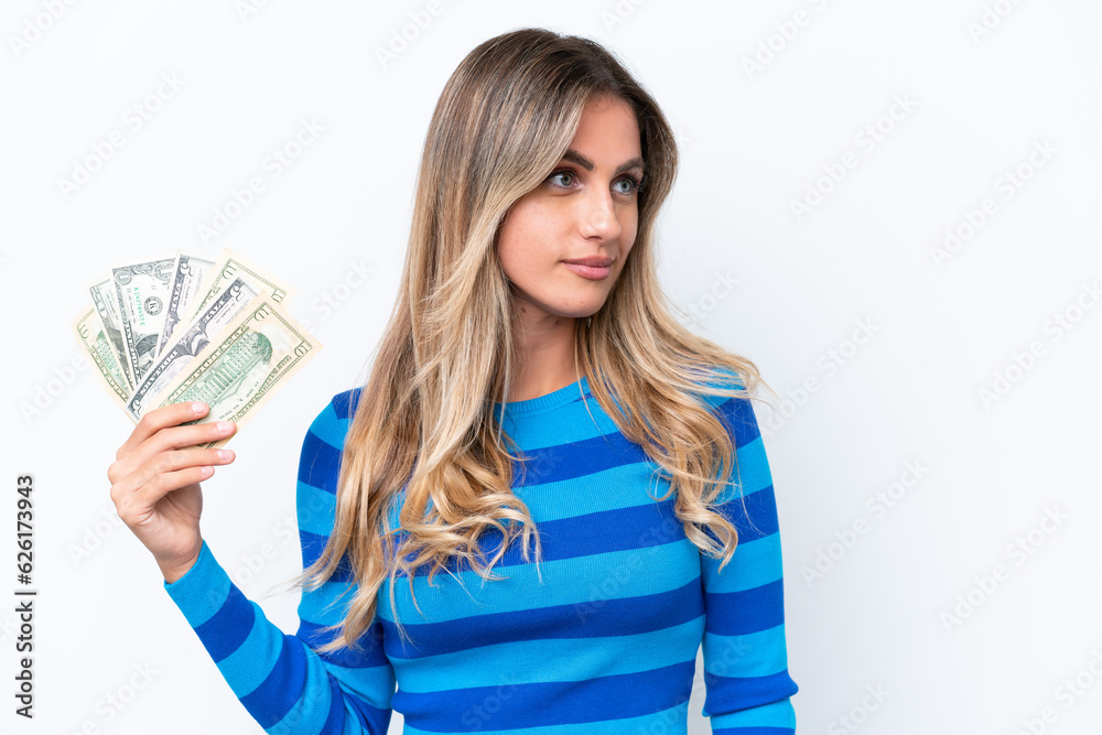 Young Uruguayan woman taking a lot of money isolated on white background looking to the side Young Uruguayan woman taking a lot of money isolated on white background looking to the side