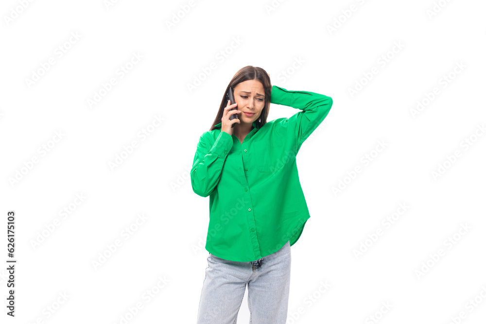 well-groomed bright young brown-haired female model with brown eyes in a green shirt speaks on the phone on a white background with copy space well-groomed bright young brown-haired female model with brown eyes in a green shirt speaks on the phone on a white background with copy space