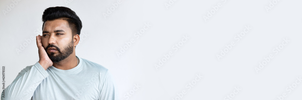 Fototapeta premium Young South Asian Man suffering from Toothache, Tooth decay, Tooth pain, gingivitis, Seeking Dental Pain Relief and Oral Health Care