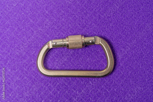 One carabiner for montaineering and climbing on a purple backround: topview with a lot of copyspace