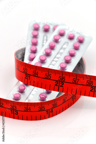 Contraceptive pill strips and red tape measurement.