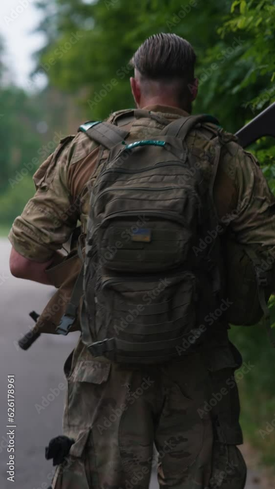 A soldier, armed with a weapon and carrying a backpack, is walking on the road. A soldier, armed with a weapon and carrying a backpack, is walking on the road.