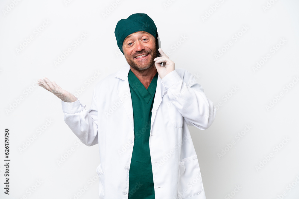Middle age surgeon in green uniform isolated on white background keeping a conversation with the mobile phone with someone Middle age surgeon in green uniform isolated on white background keeping a conversation with the mobile phone with someone