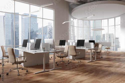 Stylish coworking interior with pc desktop and table near panoramic window