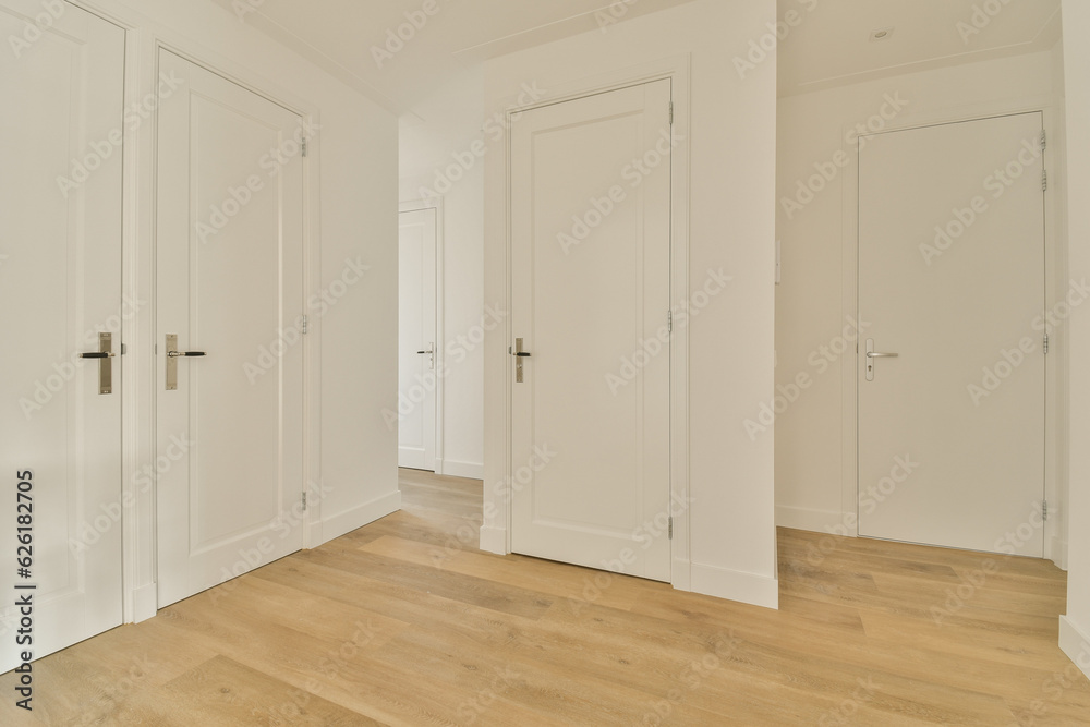 an empty room with white doors and wood flooring on the right side of the room, there is no one in sight an empty room with white doors and wood flooring on the right side of the room, there is no one in sight