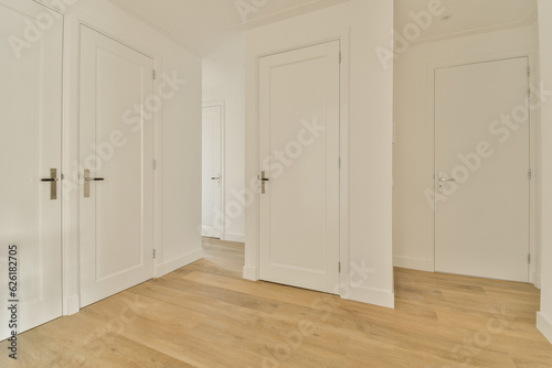 an empty room with white doors and wood flooring on the right side of the room, there is no one in sight