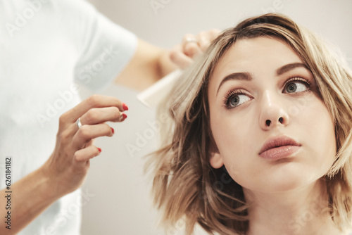 Hairdresser does hairstyle cute pretty young woman in beauty salon