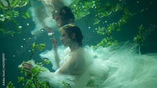 beautiful underwater fairy in mysterious undersea blooming garden, female figure moving slowly