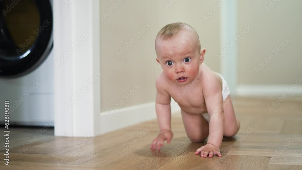 Happy and curious child explores his house by crawling on parquet floor. Happiness and satisfaction on face of child. Baby crawls across floor towards his parent. Baby learns to move on floor at home Happy and curious child explores his house by crawling on parquet floor. Happiness and satisfaction on face of child. Baby crawls across floor towards his parent. Baby learns to move on floor at home
