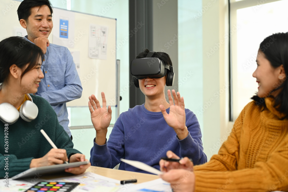 Male wearing headset having virtual reality experience, start up team discussing about new digital projects together Male wearing headset having virtual reality experience, start up team discussing about new digital projects together