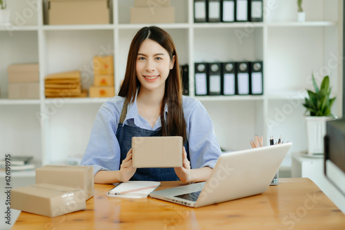 Portrait of Asian young woman SME working using smartphone or tablet taking receive and checking online purchase shopping order to business online concept.