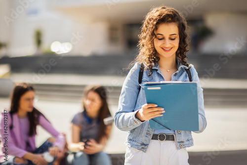 Student standing with her note-book while her friends are studying behind her