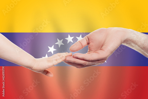 Velezuelan baby and parent hands on the background of flag of Venezuela Help, aid, support, charity concept