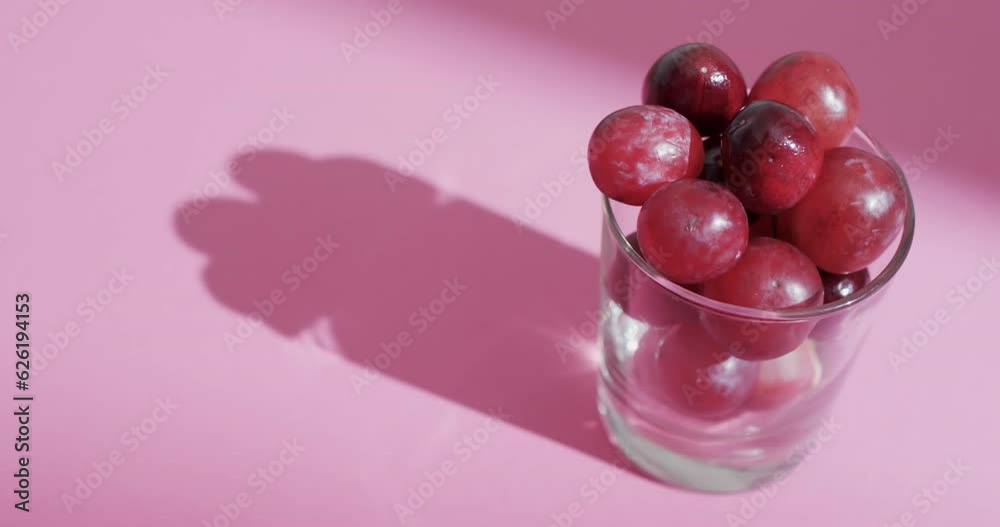 Video of red grapes in glass with copy space on pink background