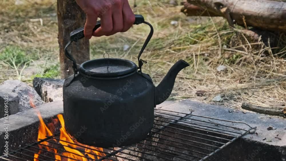 A smoked kettle is boiling water over the selfmade tourist stove made