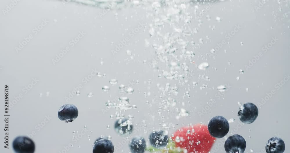 Video of berries falling into water with copy space on white background