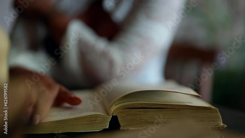 closeup view of old book with poems and love novels, woman flipping pages, vintage and retro style photo