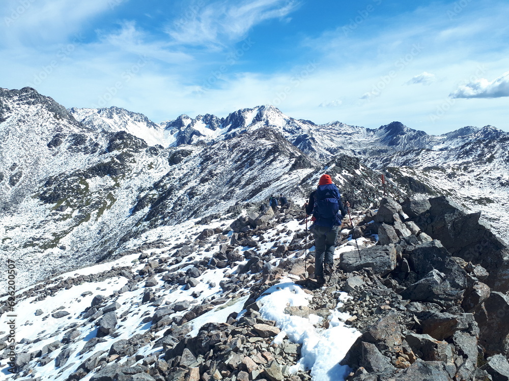 Hiker walking on the mountain's peak in snow