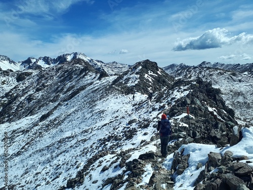 Hiker walking on the mountain's peak in snow