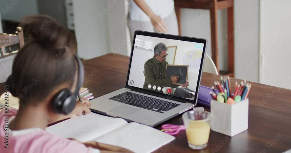 Diverse schoolgirl having class on laptop video call with male teacher in slow motion Diverse schoolgirl having class on laptop video call with male teacher in slow motion