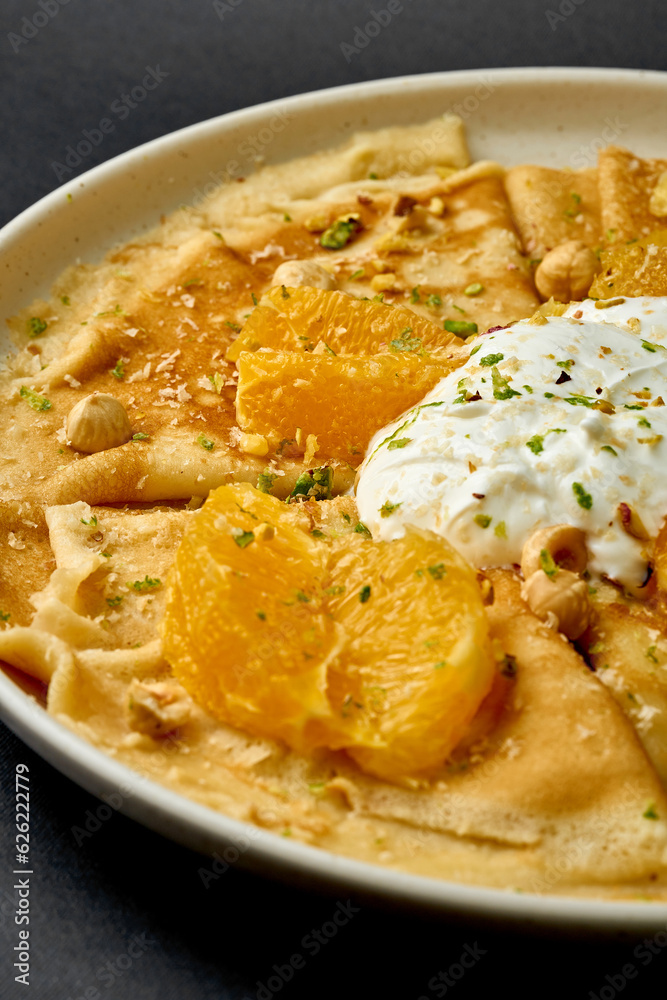 Crepes suzette with ice cream, nuts and oranges on a dark background. Crepes suzette with ice cream, nuts and oranges on a dark background.