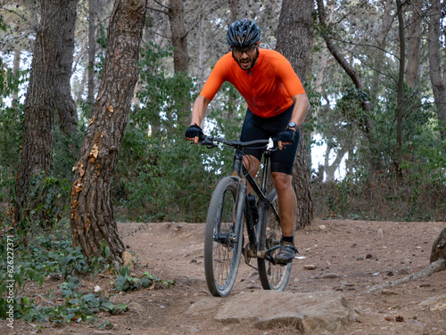 Man riding mtb mountain bike through forest. Mountain bike trail, extreme sport activities © gonzagon