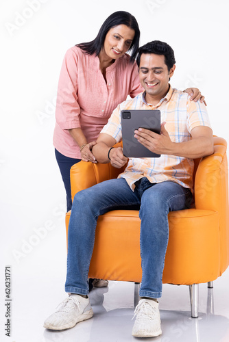 Mother and son shopping online together on tablet, while relaxing at home. © G-images