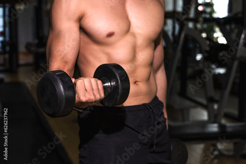 Close up strong six packs fitness man holding dumbbell in gym, Fitness in the gym