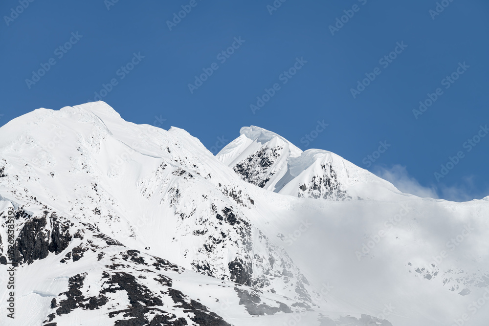 Sun and shadows on a snow covered mountain with clouds and mist, Alaska, USA Sun and shadows on a snow covered mountain with clouds and mist, Alaska, USA
