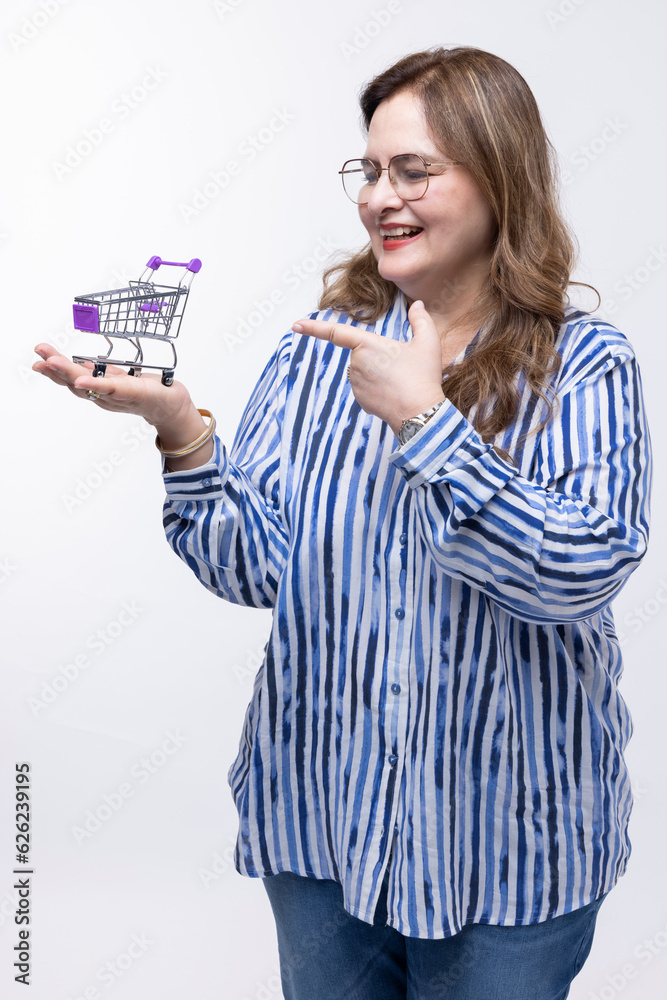Smiling casual woman standing with small empty shopping cart basket on her palm Smiling casual woman standing with small empty shopping cart basket on her palm