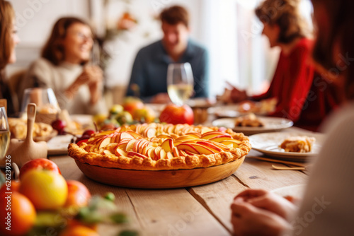 Thanksgiving family dinner. Traditional apple pie and vegan meal close up, with blurred happy people around the table celebrating the holiday. photo